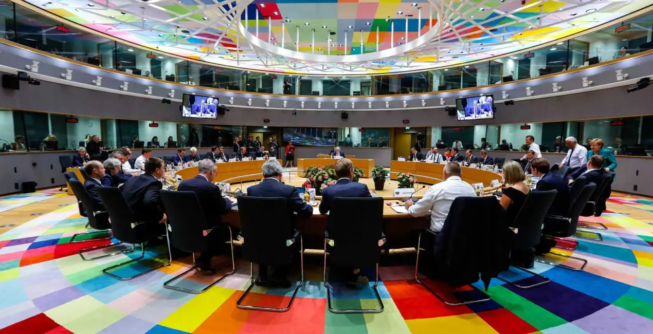 De leden van de Europese raad vergaderen aan een ronde tafel.