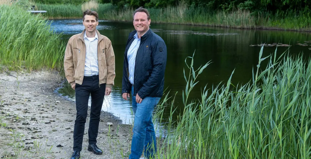 Twee medewerkers staan voor een rivier