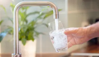 Mannenhand vult glas met kraanwater